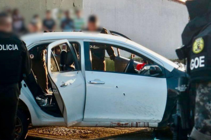 Agentes policiales custodian un vehículo involucrado en la masacre ocurrida en Socio Vivienda 2, la tarde del jueves 6 de marzo.