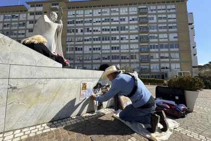 Un artista dibuja ante la escultura del papa Juan Pablo II, a las puertas del Hospital Gemelli donde permanece ingresado el papa.