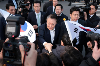 El presidente destituido, Yoon Suk Yeol, estrecha la mano de un partidario al llegar frente a su residencia oficial después de ser liberado de su detención, el 8 de marzo de 2025.