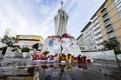 Un feligrés católico reza junto a la estatua de Juan Pablo II, frente al hospital Gemelli de Roma.