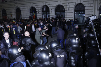 Partidarios del ultranacionalista Calin Georgescu discuten con policías antidisturbios durante una protesta anoche que se volvió violenta frente a la Oficina Electoral Central.