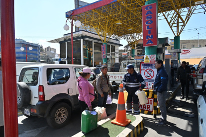 La gente espera con contenedores de plástico para comprar combustible durante un paro de transporte de 24 horas debido a la escasez de combustible en La Paz el 23 de octubre de 2024.