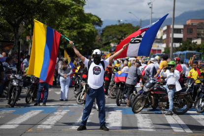 Un hombre sostiene banderas durante una manifestación este martes, en Cali (Colombia). Sindicalistas, empleados oficiales y simpatizantes del Gobierno colombiano salieron a las calles de Bogotá y otras ciudades del país para reclamar la aprobación de las reformas laboral y de la salud.