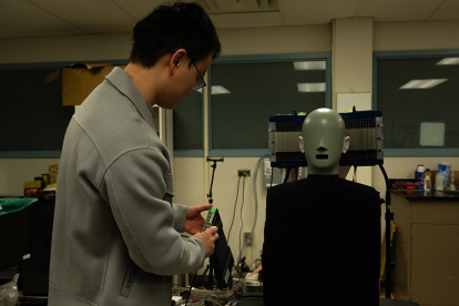 Uno de los investigadores Jia-Xin Zhong, usa un ma niquí con micrófonos en las orejas para medir la presencia o ausencia de sonido a lo largo de una trayectoria ultrasónica.