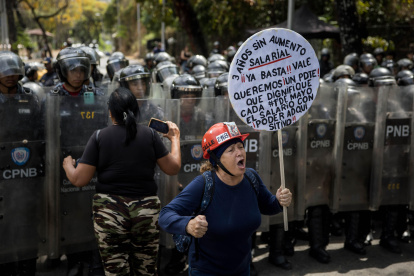 Personas se manifiestan durante una protesta frente a miembros de la Policía Nacional Bolivariana (PNB) que custodian los accesos a la Universidad Central de Venezuela (UCV), en Caracas (Venezuela).