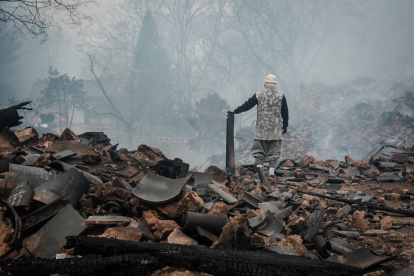 Un auxiliar caminando sobre los escombros causados tras la expansión de los incendios forestales surcoreanos.