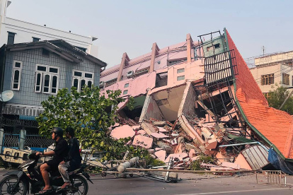 Gente pasa al frente de un edificio colapsado tras un terremoto ocurrido en Birmania el 28 de marzo de 2025.