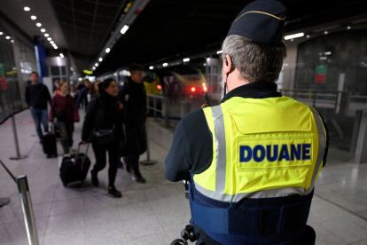 Un agente de aduanas francés vigila los viajeros de un aeropuerto.