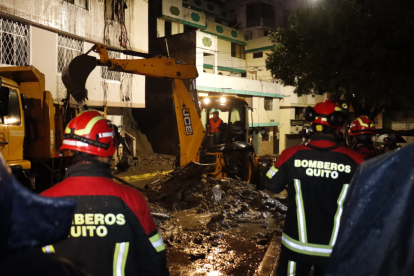 Los bomberos y maquinaria pesada trabajan para retirar los escombros tras el deslizamiento en Guápulo, que afectó varias viviendas.