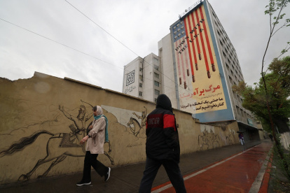 Transeúntes pasan por calles iraníes con el trasfondo de propaganda antiestadounidense