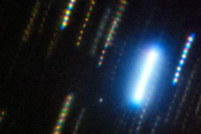 Imagen compuesta del asteroide 2024 YR4 capturada con el telescopio Gemini Sur (Chile) en febrero de 2025. El asteroide es el punto nebuloso en el centro de la imagen, que está rodeado de coloridas estelas de estrellas, las cuales muestran el paso del tiempo y el movimiento del cielo nocturno en una imagen fija.