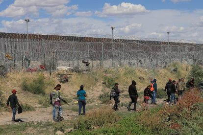 Migrantes caminan cerca del muro que separa la frontera estadounidense en Ciudad Juárez, Chihuahua (México).