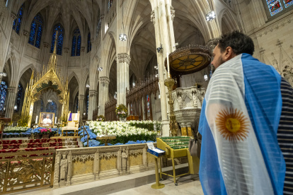 Una persona que lleva la bandera de Argentina mira una imagen del fallecido Papa Francisco dentro de la Catedral de San Patricio el día de su fallecimiento en Nueva York, Nueva York, EE. UU., el 21 de abril de 2025.