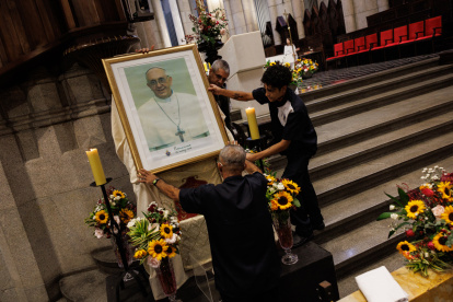 Personas acomodan un retrato del papa Francisco antes de una misa misa en honor este lunes, en la Catedral Metropolitana de la Sé, en el centro de la ciudad de São Paulo (Brasil).