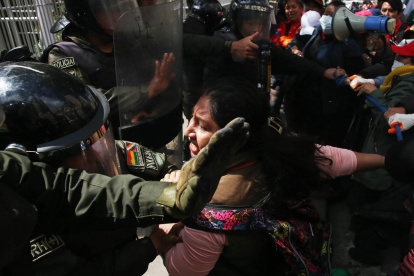 Integrantes de la Policía Boliviana y maestros al enfrentarse este lunes, 21 de abril, durante una manifestación frente al Ministerio de Educación, en La Paz (Bolivia).