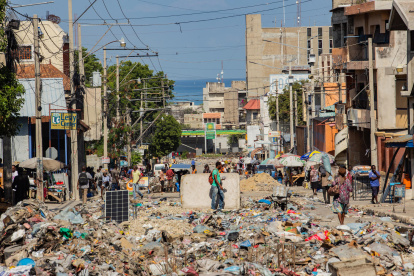 decenas de personas al caminar por una calle en ruinas y llena de basura cerca al Palacio Nacional, en Puerto Príncipe (Haití).
