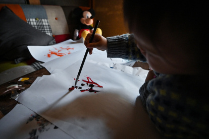 Esta foto tomada el 8 de abril de 2025 muestra a la artista "Pulgarcita" (derecha), de 21 meses, usando un pincel para pintar en la casa de la familia en Tokio.