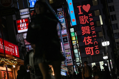 Personas caminando por una calle junto al letrero de neón "I love Kabukicho" en la zona de entretenimiento del distrito rojo