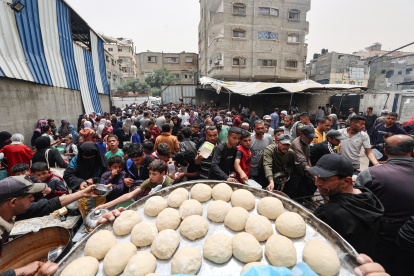 Palestinos se reúnen para recibir una comida caliente en un centro de distribución de alimentos en el campamento de refugiados de Nuseirat