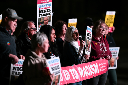 Manifestantes sostienen cartel con imagen del presidente y diputado del partido de ultraderecha británico Reform UK, Nigel Farage, que dice "Se busca por racismo", el 1 de mayo de 2025.