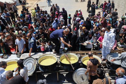 Palestinos desplazados hacen cola para recibir una porción de comida caliente en un comedor benéfico en el campo de refugiados de Nuseirat, en el centro de la Franja de Gaza, el 5 de mayo de 2025.