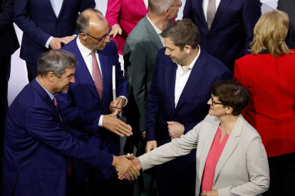 El líder de la Unión Socialcristiana (CDU), Friedrich Merz (al fondo, izq.), estrecha la mano del copresidente del SPD, Lars Klingbeil, tras firmar un acuerdo de coalición para formar el nuevo gobierno.