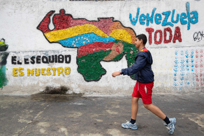 Fotografía del 2 de abril del 2025 de una persona caminando frente a un mural con el mapa de Venezuela en Caracas (Venezuela).