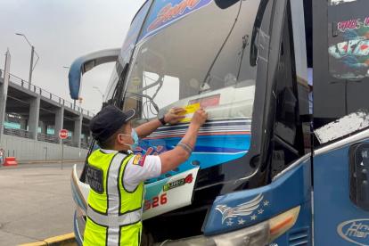 Un agente de la CTE coloca un sticker en uno de los buses sancionados, la mañana de este jueves 22 de mayo.