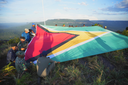 hombres desplegando una bandera de Guyana en la montaña Pakrampa, en la aldea de Arau, región Esequibo (Guyana).