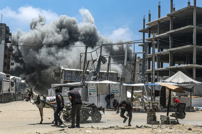 Palestinos intentan refugiarse mientras se eleva el humo tras un ataque aéreo israelí al oeste de la ciudad de Gaza, en la Franja de Gaza, el 23 de mayo de 2025.