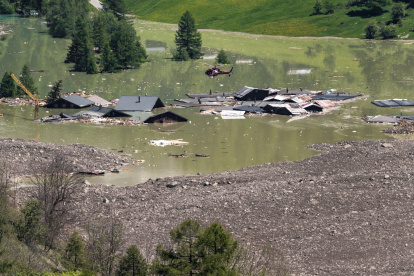 Un helicóptero vuela sobre los escombros y las casas destruidas del pueblo de Blatten, ahora sumergido en el río obstruido Lonza en Wiler, el 30 de mayo de 2025.
