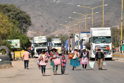 Personas caminan por una carretera tras un bloqueo realizado por seguidores del exmandatario Evo Morales este lunes, en Sipe Sipe en la región de Cochabamba (Bolivia).