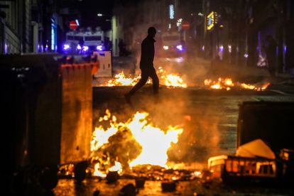 Un manifestante camina junto a un incendio en la calle durante una manifestación contra la inmigración en Ballymena, Irlanda del Norte, el 10 de junio de 2025.