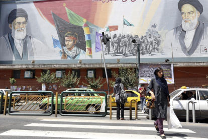 Ciudadanos iraníes caminan junto a un cartel que representa al líder supremo de Irán, ayatolá Ali Jamenei,  en una calle de Teherán, Irán.