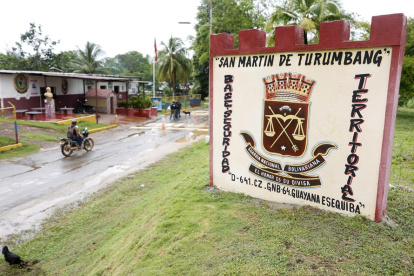 Una motocicleta pasa junto a un cartel de la Guardia Nacional Bolivariana a la entrada del pueblo de San Martín de Turumbang, estado Bolívar, Venezuela, el 26 de mayo de 2025.