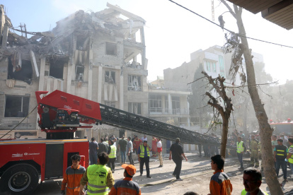 Bomberos, rescatistas y personal de seguridad trabajan alrededor de un edificio que fue alcanzado por ataques aéreos israelíes en el centro de Teherán, Irán, el 13 de junio de 2025.