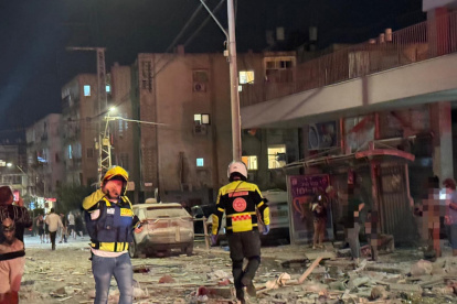Integrantes de equipos de emergencia, bomberos y policía, trabajan en el área donde un proyectil iraní impactó provocando el derrumbe de un edificio en la madrugada de este domingo.