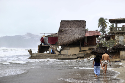 Personas que observan los estragos causados por el fuerte oleaje e intensas lluvias, en Acapulco (México).