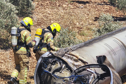 Dos bomberos observan los restos de un misil balístico iraní en un olivar de Galilea.