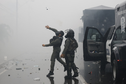 Un integrante de la Unidad de Control de Multitudes (UCM) lanza una granada de gas lacrimógeno durante una manifestación este sábado