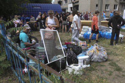 Residentes sentados con sus pertenencias cerca de un edificio residencial dañado tras un bombardeo masivo ruso en la ciudad de Dnipropetrovsk, Ucrania