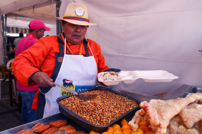 Fotografía de archivo fechada el 09 de agosto de 2024 de una mujer sirviendo alimentos típicos en Quito (Ecuador).