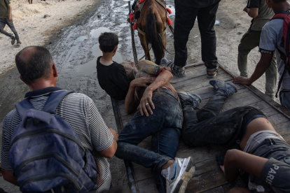 Palestinos ayudan a dos hombres heridos mientras intentaban recoger paquetes de alimentos, en la franja norte de Gaza, el 22 de junio de 2025.