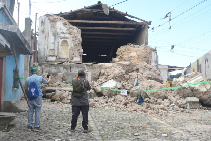 Personas observan este miércoles una edificación destruida por los temblores ocurridos el martes, en Santa María de Jesús (Guatemala).