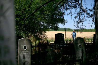 Mirko Bogicevic, de 68 años, residente local y cronista del pueblo, pasa por los cementerios de Kisiljevo el 23 de junio de 2025.over old headstones under a pile of undergrowth. (Photo by OLIVER BUNIC / AFP)