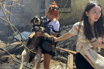Unas chicas locales llevan un perro en el lugar de un ataque con drones en Odesa, Ucrania, el 11 de julio de 2025.