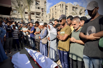 Personas rezan tras la llegada de los muertos bajo fuego israelí durante un bombardeo contra tiendas de campaña, en el sur de Gaza.