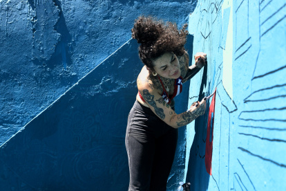 La artista Karina "Kau" Taveras pinta un mural este miércoles, en la Perla en San Juan (Puerto Rico).