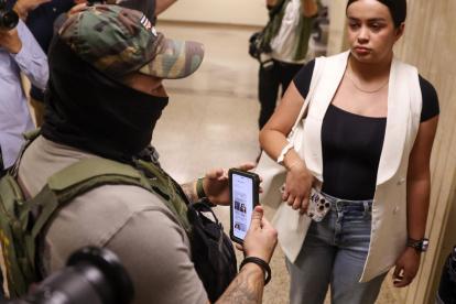 Un agente federal usa información en su teléfono mientras detiene a una mujer fuera de las audiencias del tribunal de inmigración Nueva York, Nueva York, EE. UU..