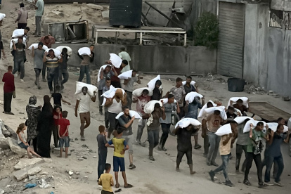 Hombres caminan cargando sacos de harina que fueron robados de un camión que transportaba alimentos, en Khan Yunis, en el sur de la Franja de Gaza, el 22 de julio de 2025.